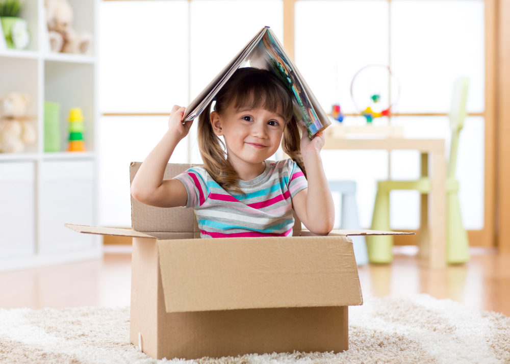 Smart,Kid,Girl,Sitting,In,Cardboard,Box,And,Holding,A